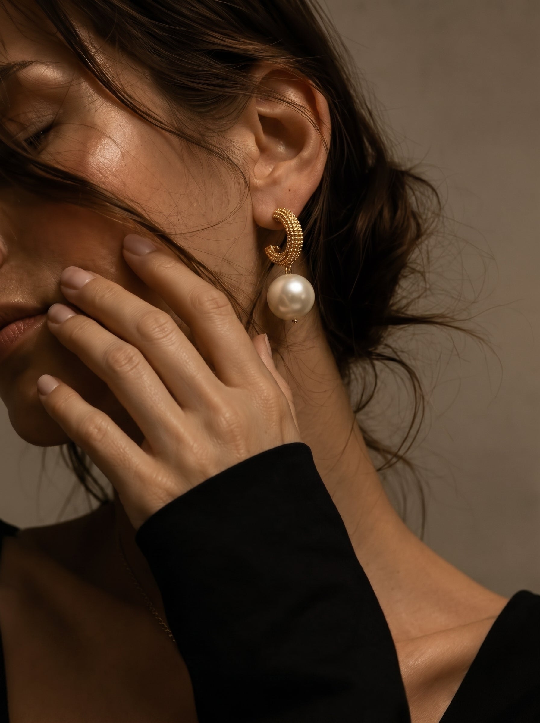 Gold-toned woven orb hoop earrings with a large white imitation pearl drop, worn by a model. @model