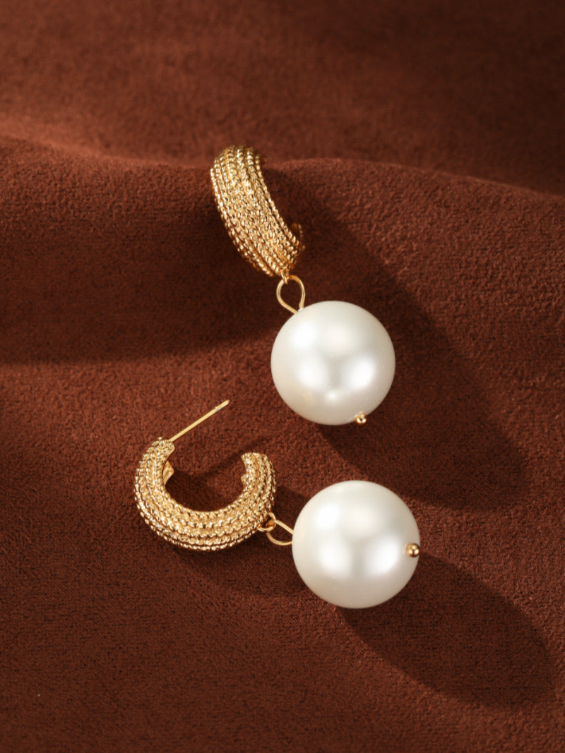 Gold-toned woven orb hoop earrings with a large white imitation pearl drop.