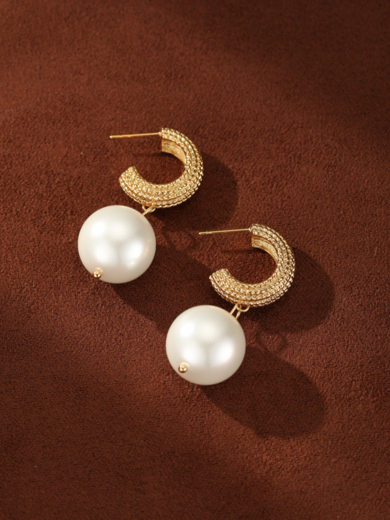 Gold-toned woven orb hoop earrings with a large white imitation pearl drop.