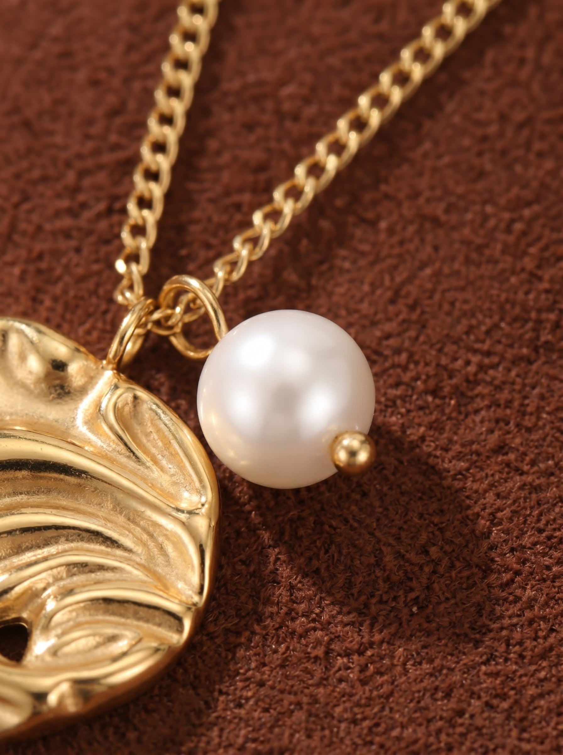 Close-up of a Zenith freshwater pearl chain necklace featuring a single white 7mm seed pearl and an organically textured gold-tone abstract pendant on a delicate gold chain.@pearl