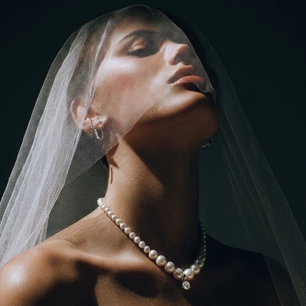 Close-up of a modern bride wearing a tulle veil and a delicate bridal pearl drop necklace, embodying Parisian quiet luxury.