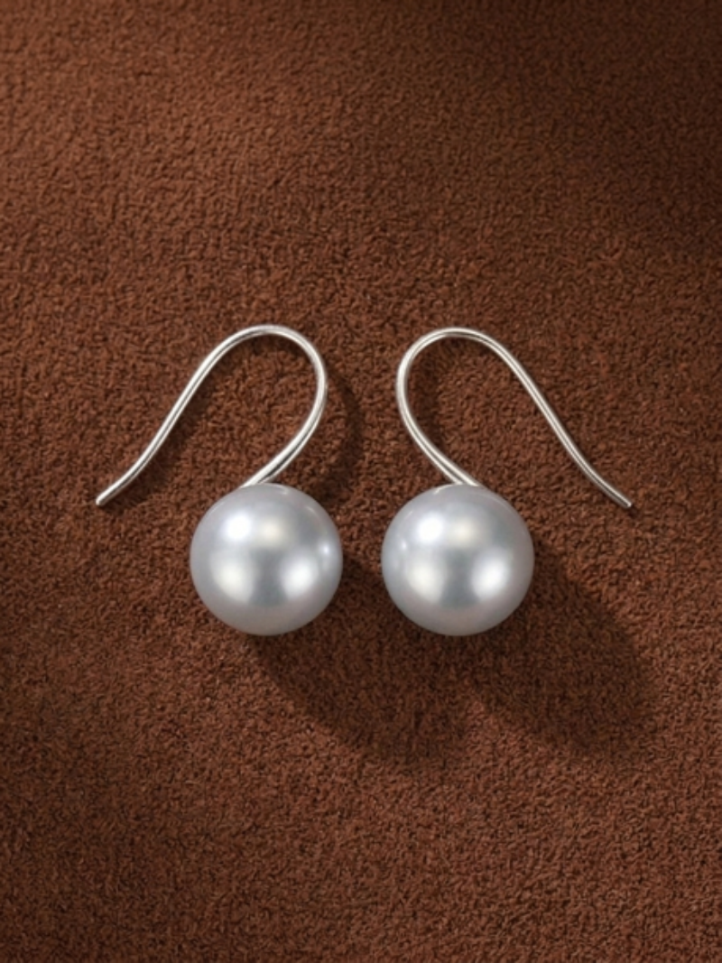 A pair of Alight Akoya Pearl Hoop Earrings featuring 9mm lustrous black pearls suspended from minimalist silver hoops, displayed on a textured brown background.