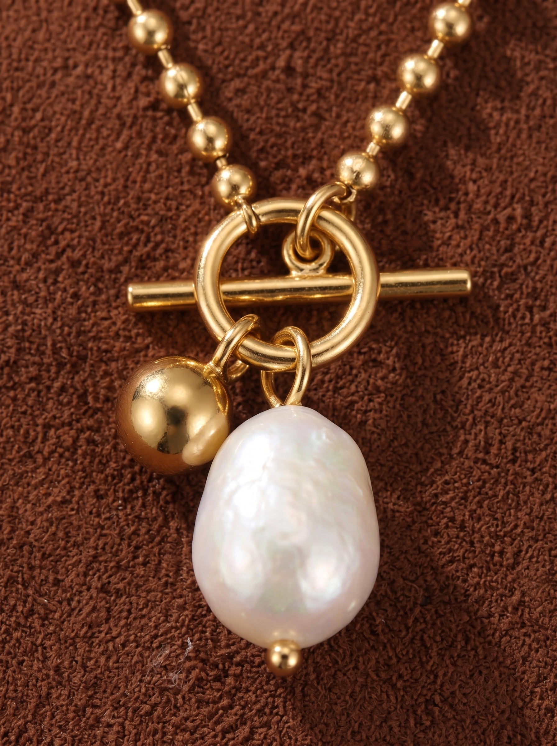 Gold-toned chunky ball chain necklace featuring a toggle clasp and a large, irregular white freshwater pearl pendant. @pearl