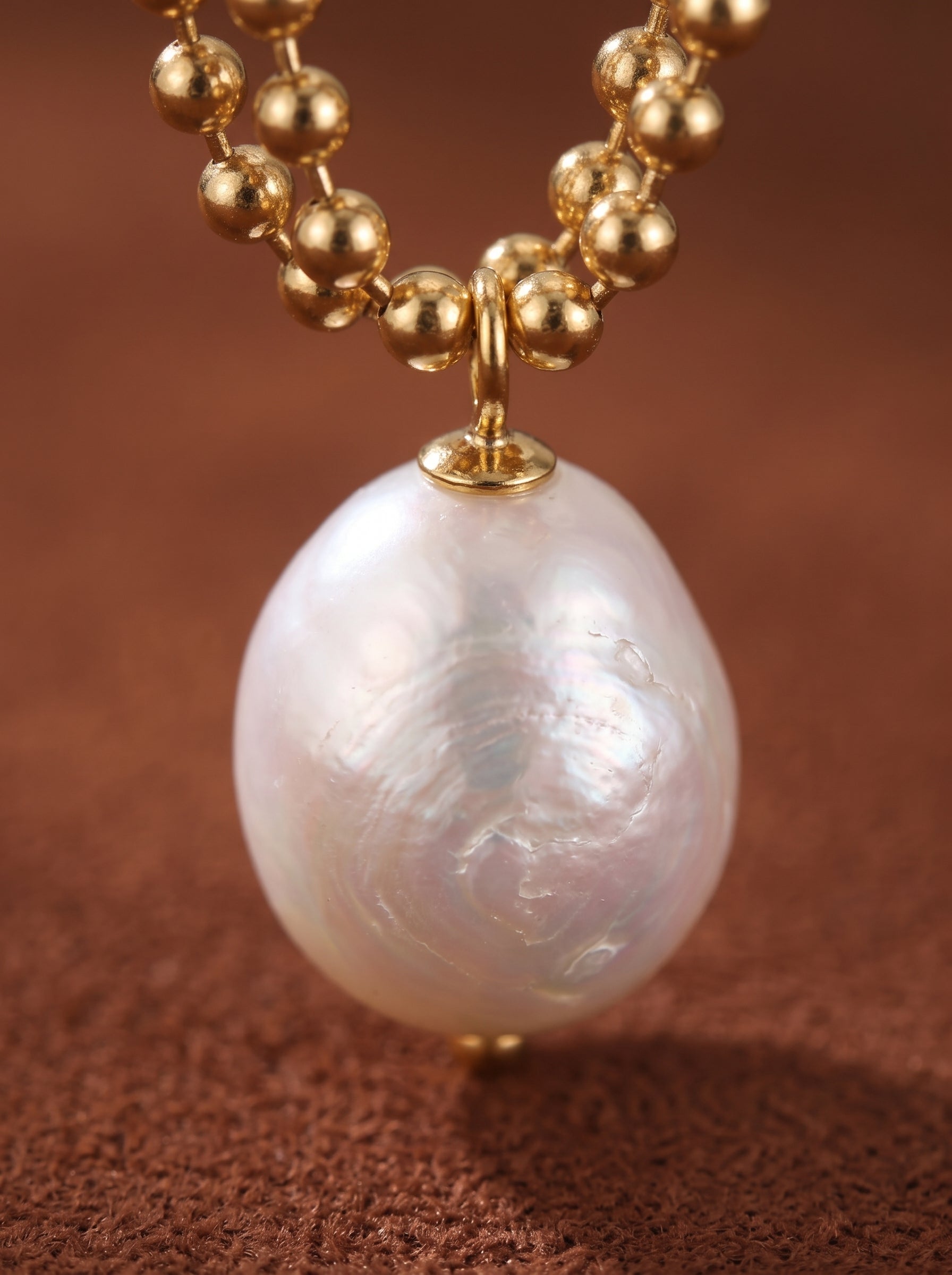 Aperture Freshwater Pearl Drop Earrings feature a lustrous 8mm white freshwater pearl with iridescent overtones, suspended from a delicate gold-tone beaded chain. @pearl