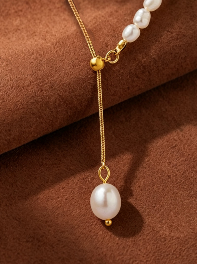 Apex Freshwater Pearl Long Lariat Necklace with a single lustrous pearl drop and adjustable gold-tone chain featuring seed pearls, on a brown textured background.