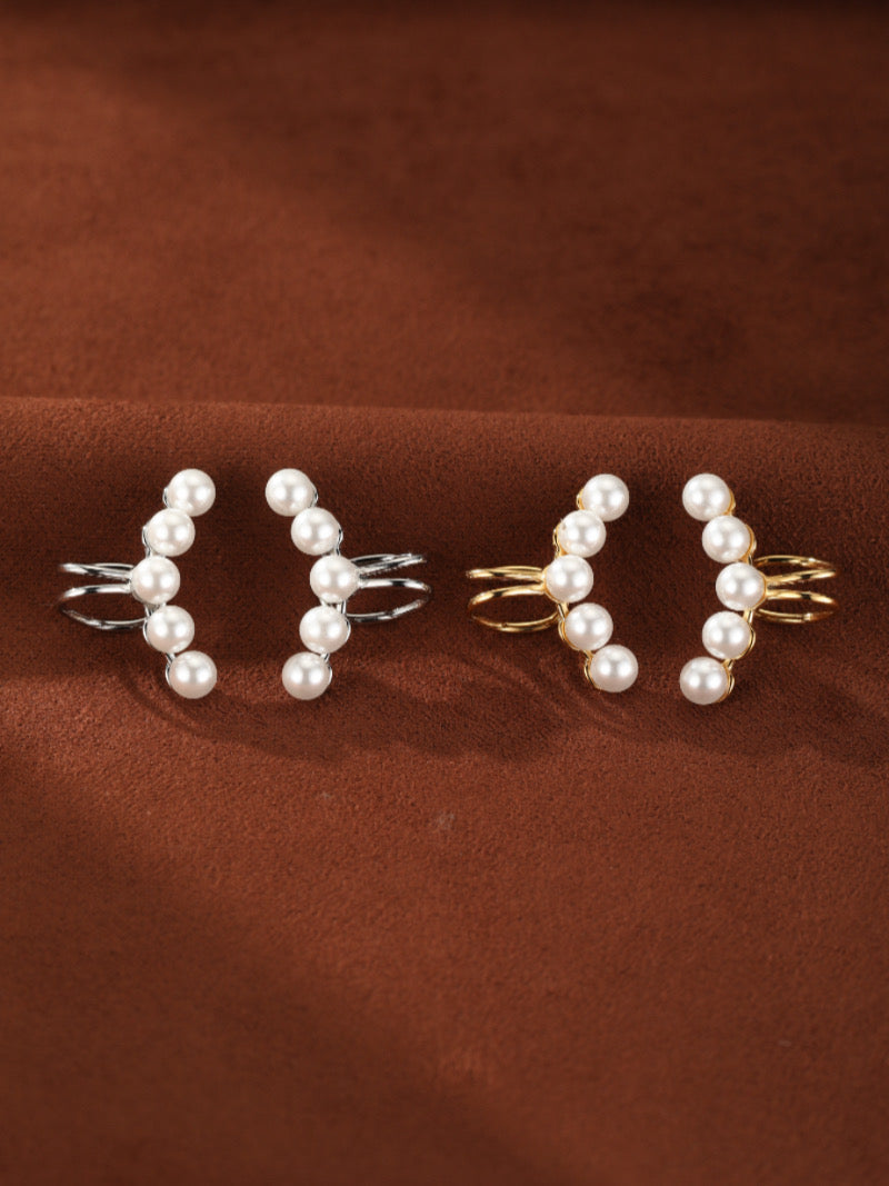 Deux paires de boucles d'oreilles ear cuff Ascent en perle d'eau douce, l'une argentée et l'autre dorée, chacune présentant de multiples perles rondes blanches de 5 mm remontant le lobe de l'oreille.