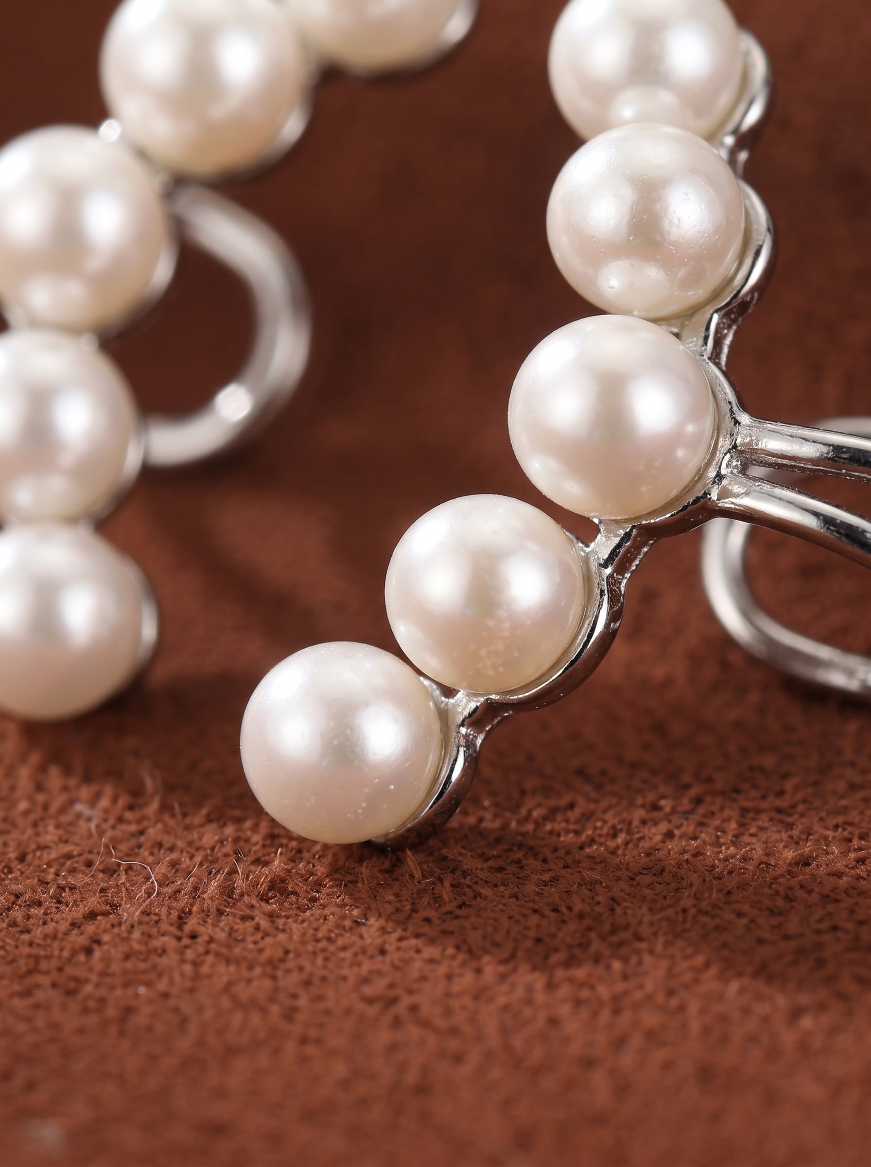 Photo en gros plan de bijoux d'oreille Ascent en perle d'eau douce, révélant les lustrées perles blanches de 5 mm serties sur une courbe métallique ton argent qui remonte le lobe de l'oreille. Les perles sont disposées pour suivre le contour naturel de l'oreille, créant une pièce de bijouterie élégante et moderne au caractère affirmé. @pearl