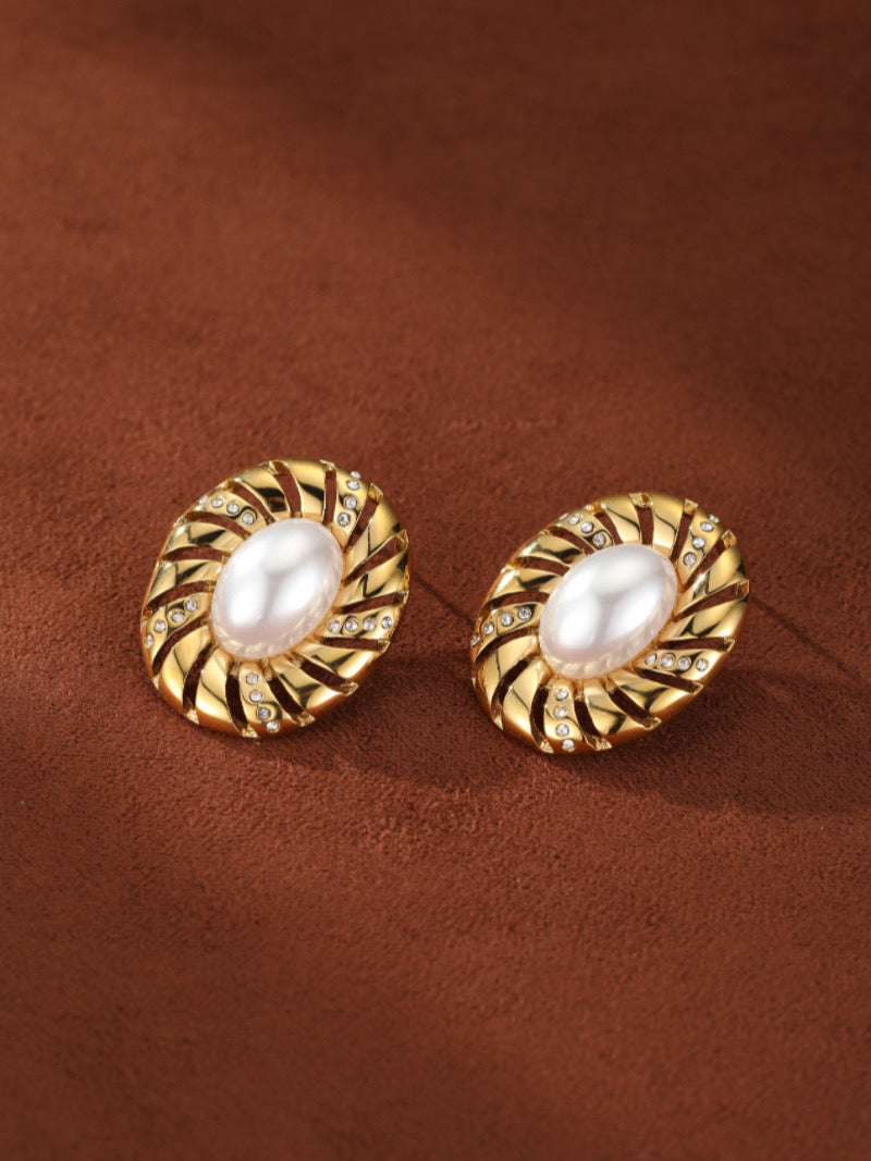 Aurelian stud earrings featuring 12mm freshwater baroque pearls set in gold-toned metal with a sculptural spiral design and sparkling accents.