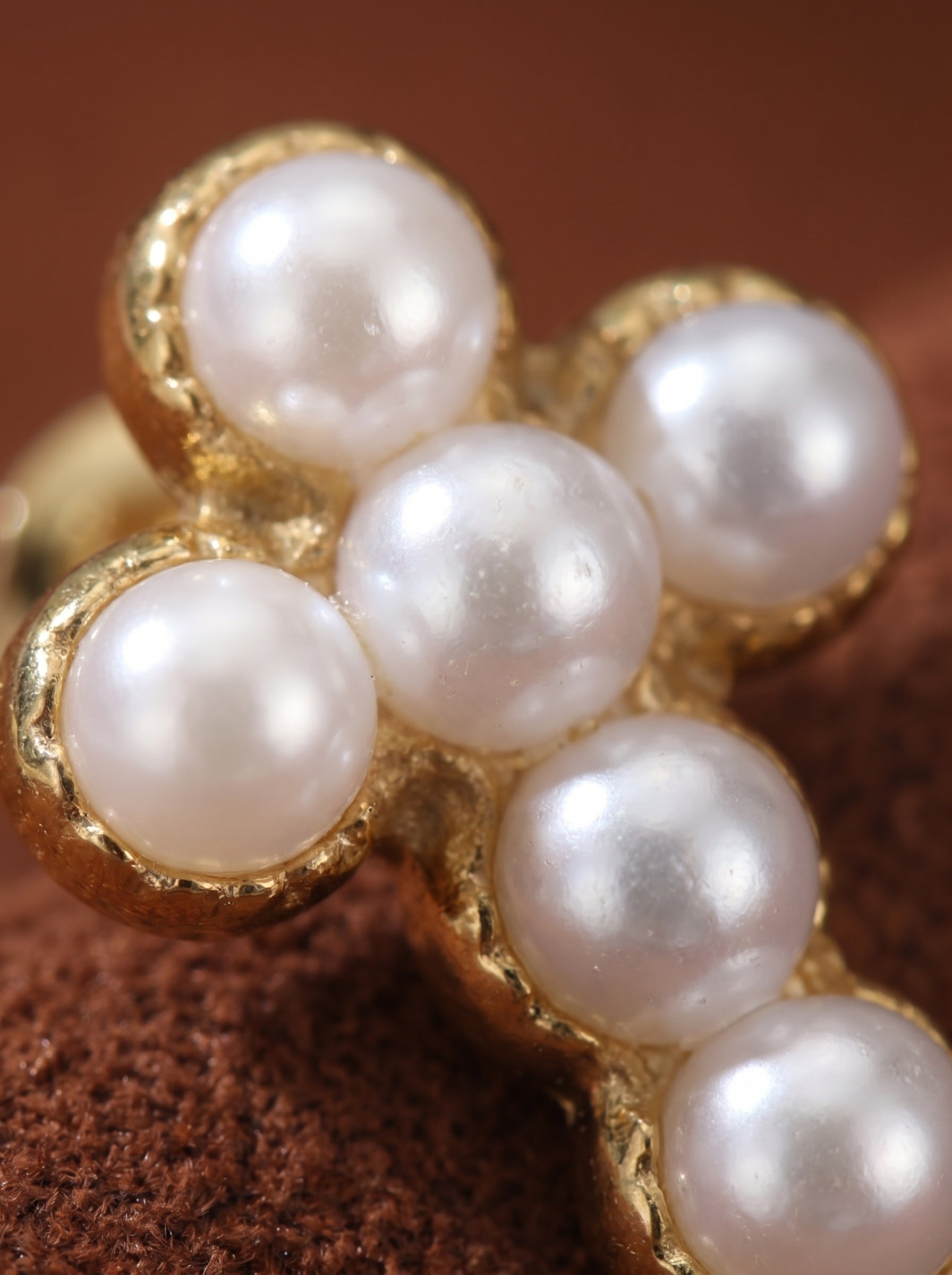 Close-up of gold-tone stud earrings shaped into a cross, adorned with small white freshwater seed pearls. @pearl