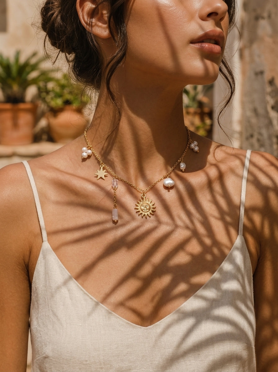 Un collier ton or avec un pendentif soleil, une breloque étoile, et des perles d'eau douce flottantes, porté par une mannequin. @model