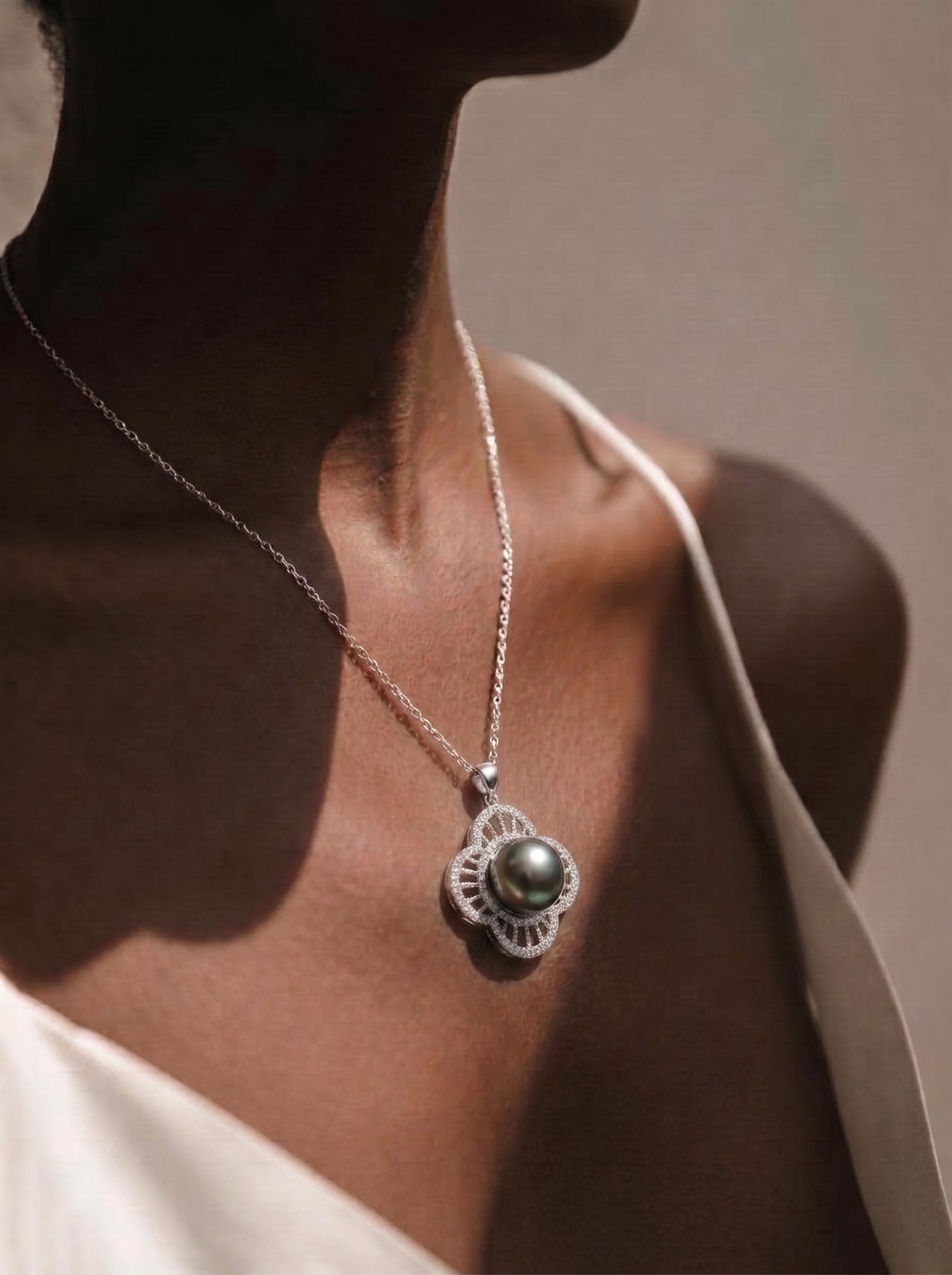 A close-up of a woman wearing a Chalice Tahitian Mabe Pearl Quatrefoil Single Pendant Necklace with a dark pearl and diamond accents @model
