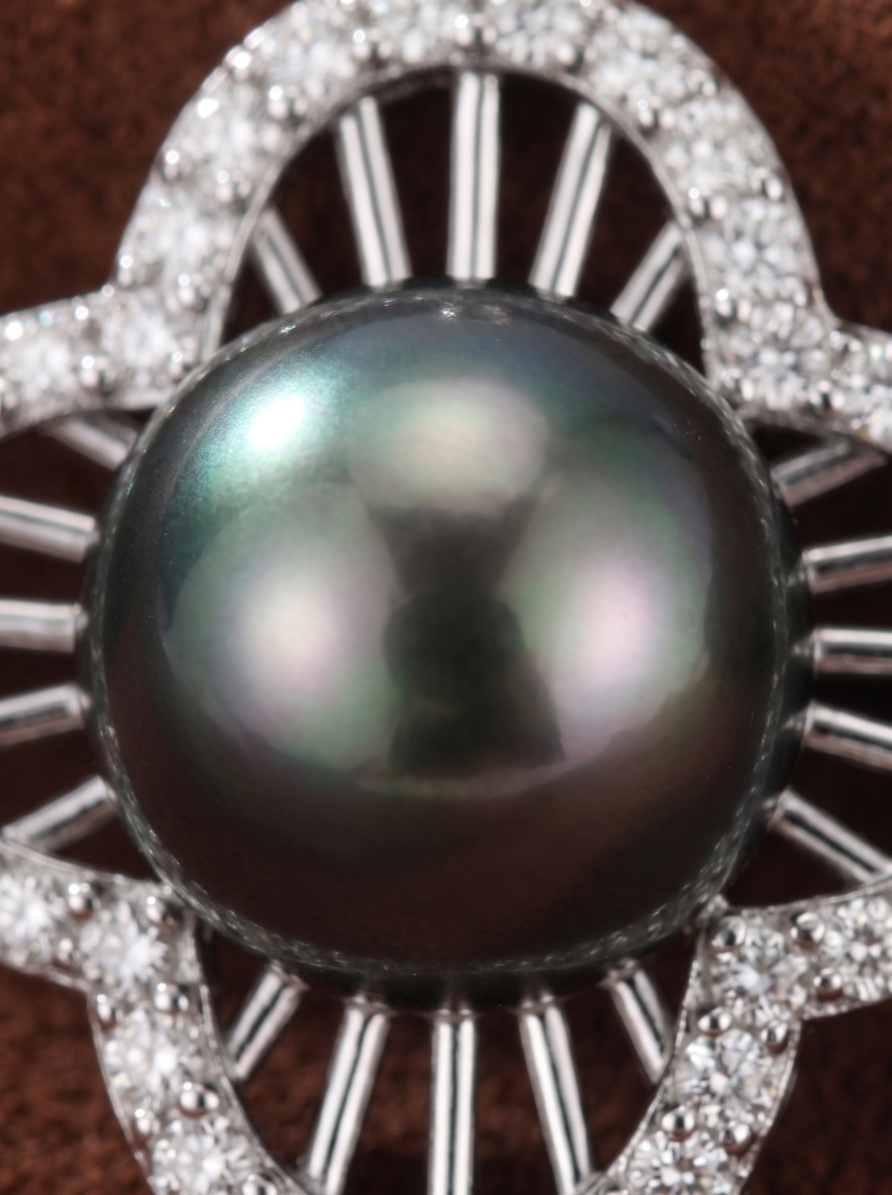 Close-up of a Chalice pendant featuring a lustrous Tahitian Mabe pearl set in a quatrefoil design adorned with sparkling accent stones, on a brown background. @pearl