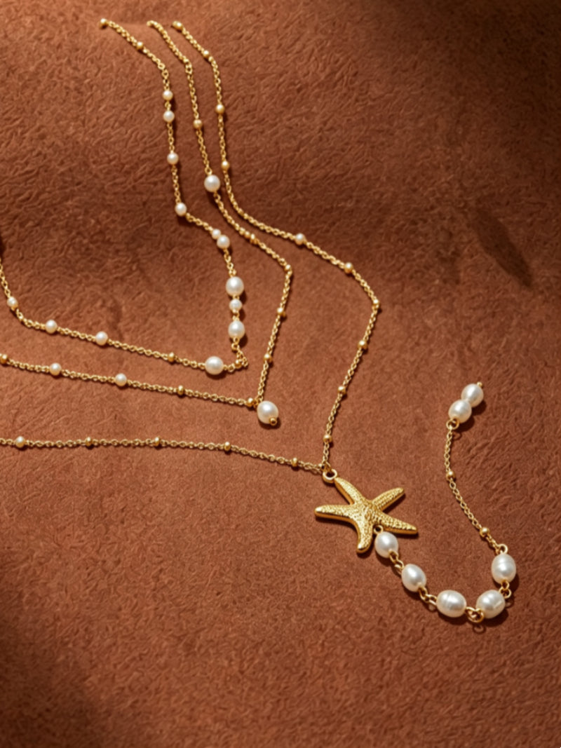 Gold layered necklace featuring a textured starfish charm and luminous freshwater pearls, with delicate bead accents.