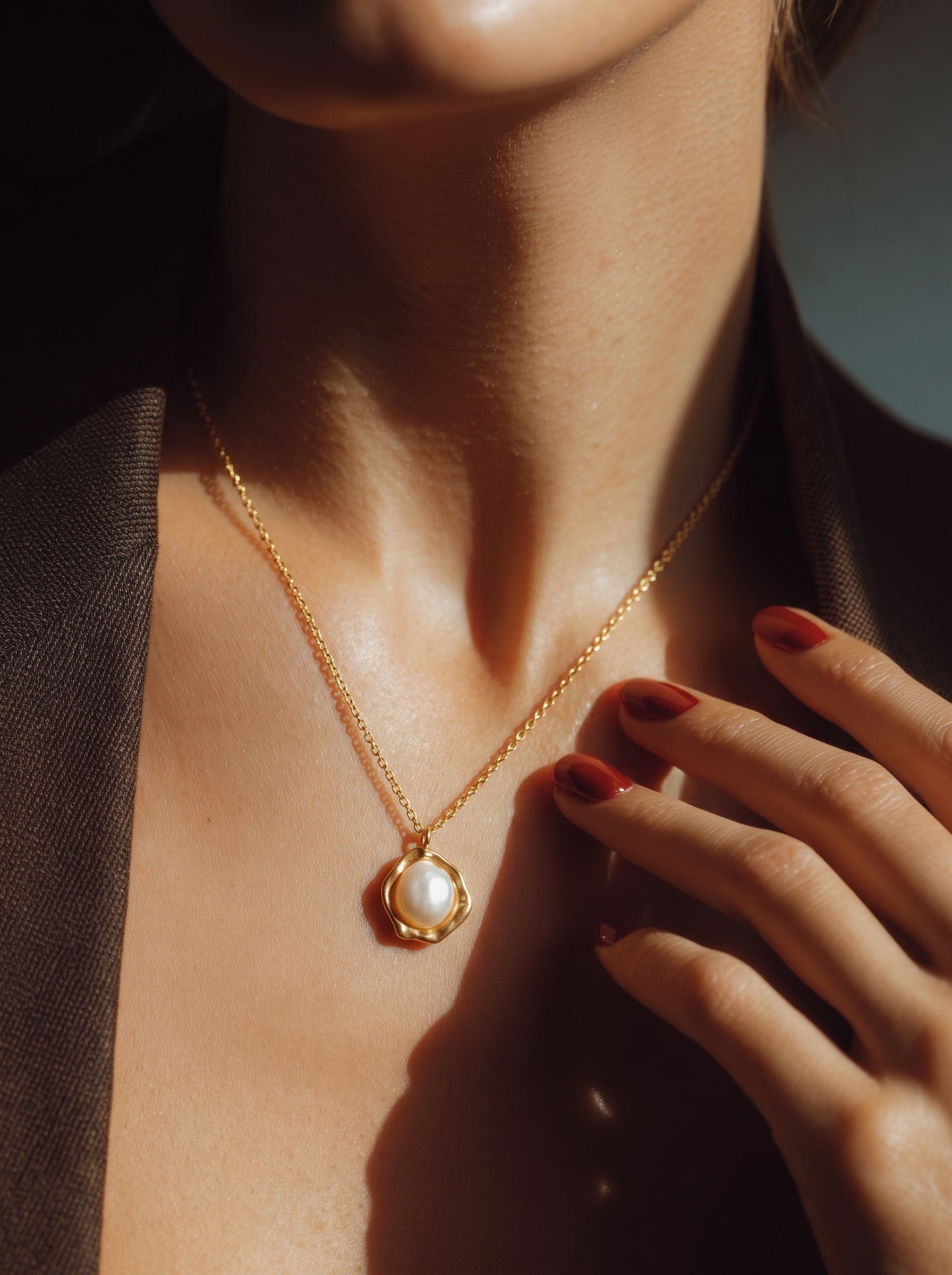 Collier pendentif Cocoon avec une perle blanche d'eau douce sertie dans un vase organique ton or sur une délicate chaîne perlée, porté par une mannequin @model