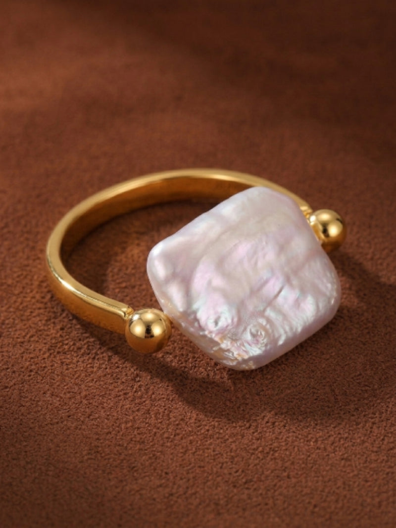 Contour Cuff Ring with a large, irregular white freshwater pearl set on a gold-toned open band with two small gold beads.