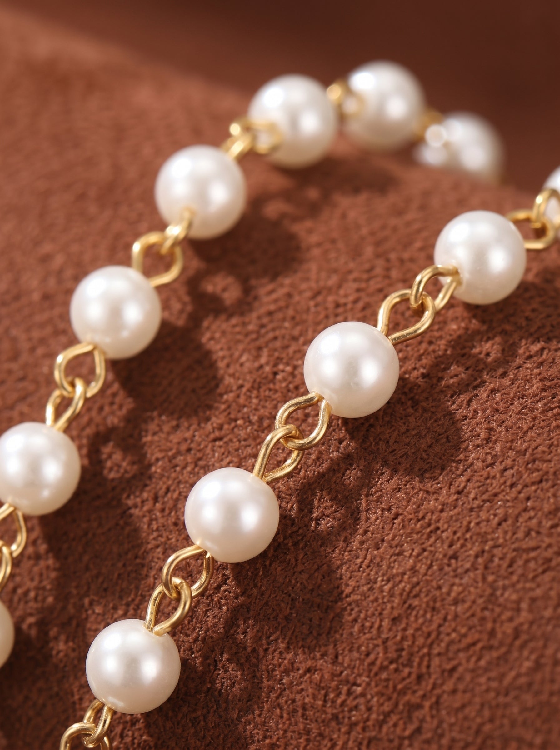 Close-up of a gold chain necklace with lustrous 4mm white imitation seed pearls spaced evenly along its length.@pearl