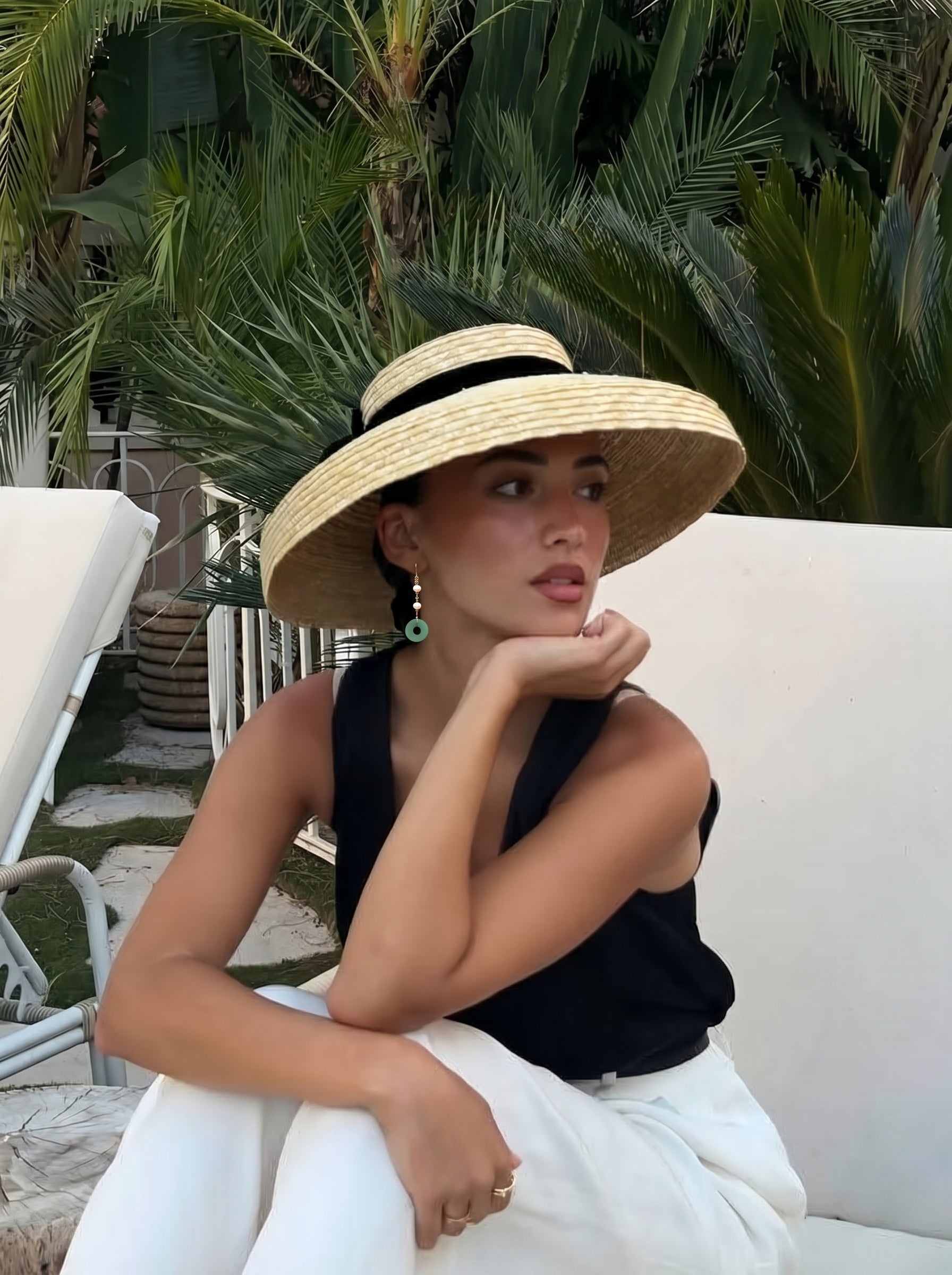 A woman wearing a wide-brimmed straw hat and a black tank top poses outdoors, accessorized with Dewdrop Freshwater Pearl Ring Dangle Earrings featuring a white pearl and a green ring. @lifestyle #lifestyle