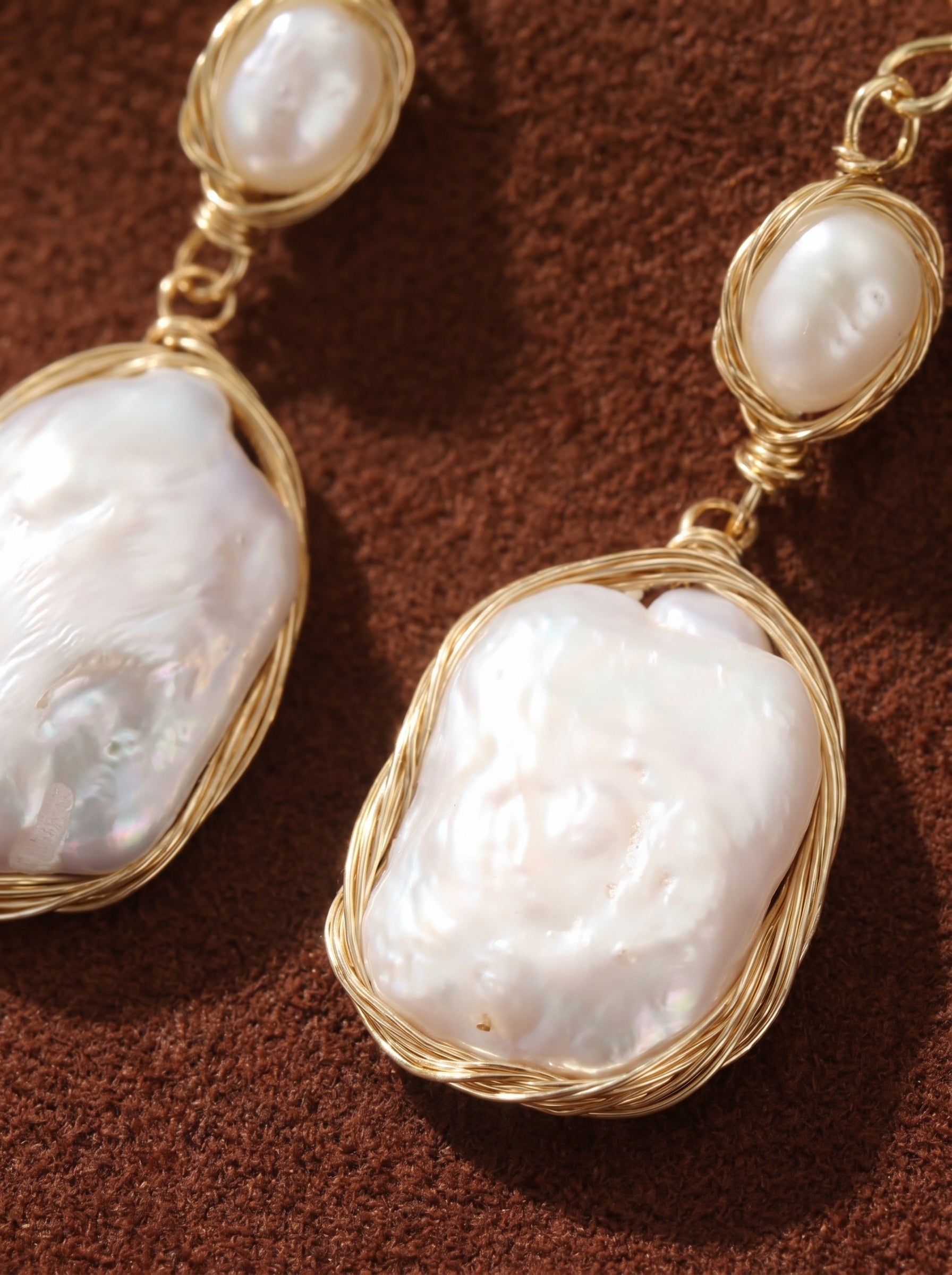 Drift freshwater pearl wire-wrapped dangle earrings featuring two irregular white baroque pearls secured with gold-toned wire on a textured brown background@pearl