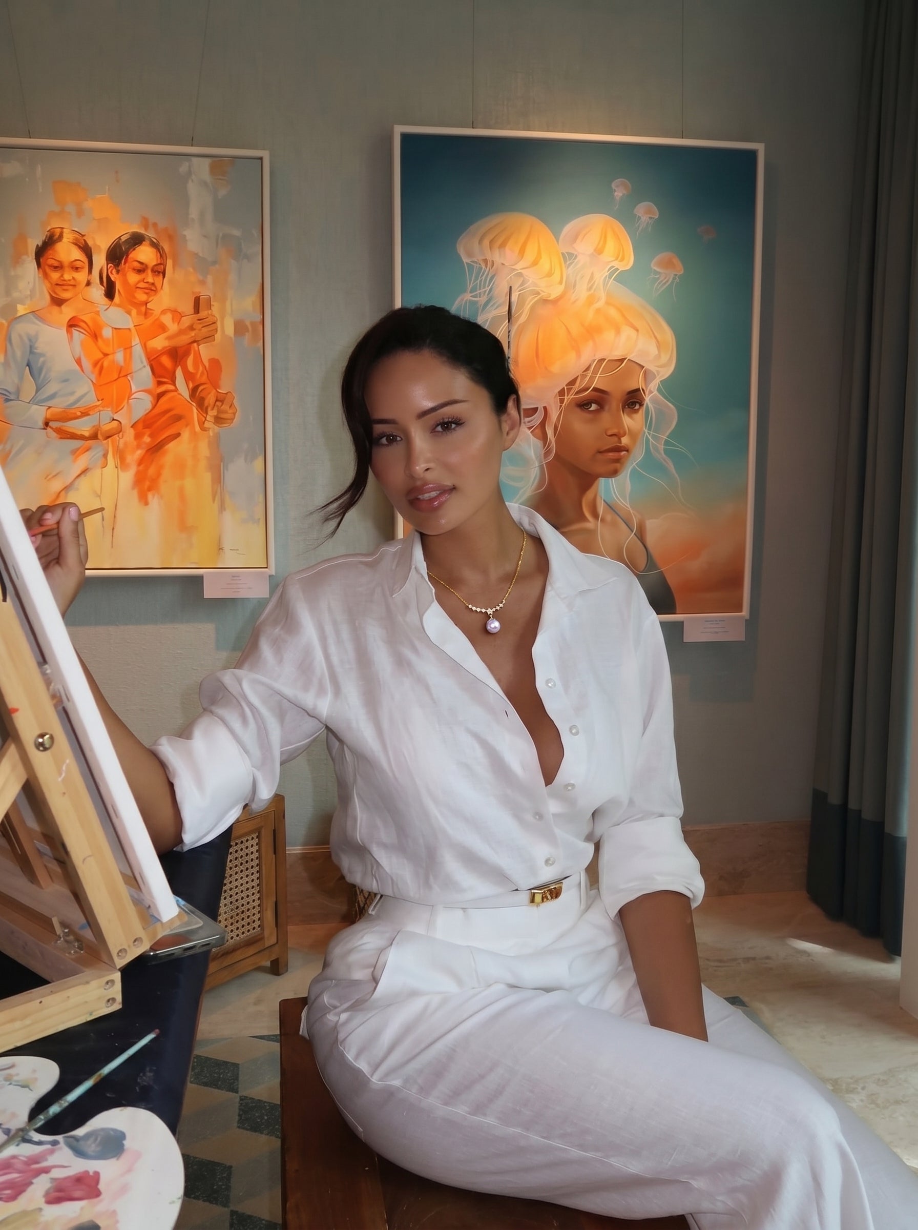 Femme portant le collier pendentif goutte en grappe d'étoiles Eclat en perle d'eau douce avec une seule perle violette pendant d'une délicate chaîne dorée, assise dans un atelier d'art. @lifestyle