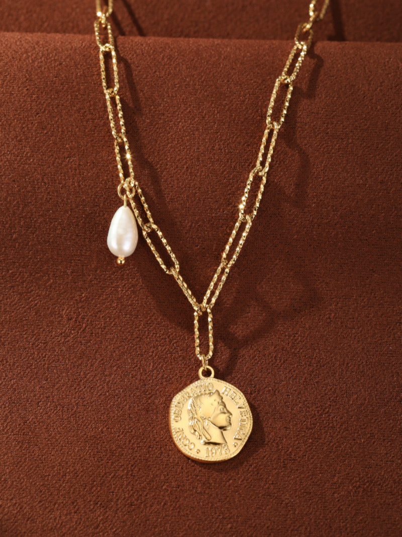 Collier à chaîne à maillons imposants dorés présentant un pendentif pièce rond avec un profil et l'année 1973, accentué d'une seule perle goutte blanche d'eau douce.