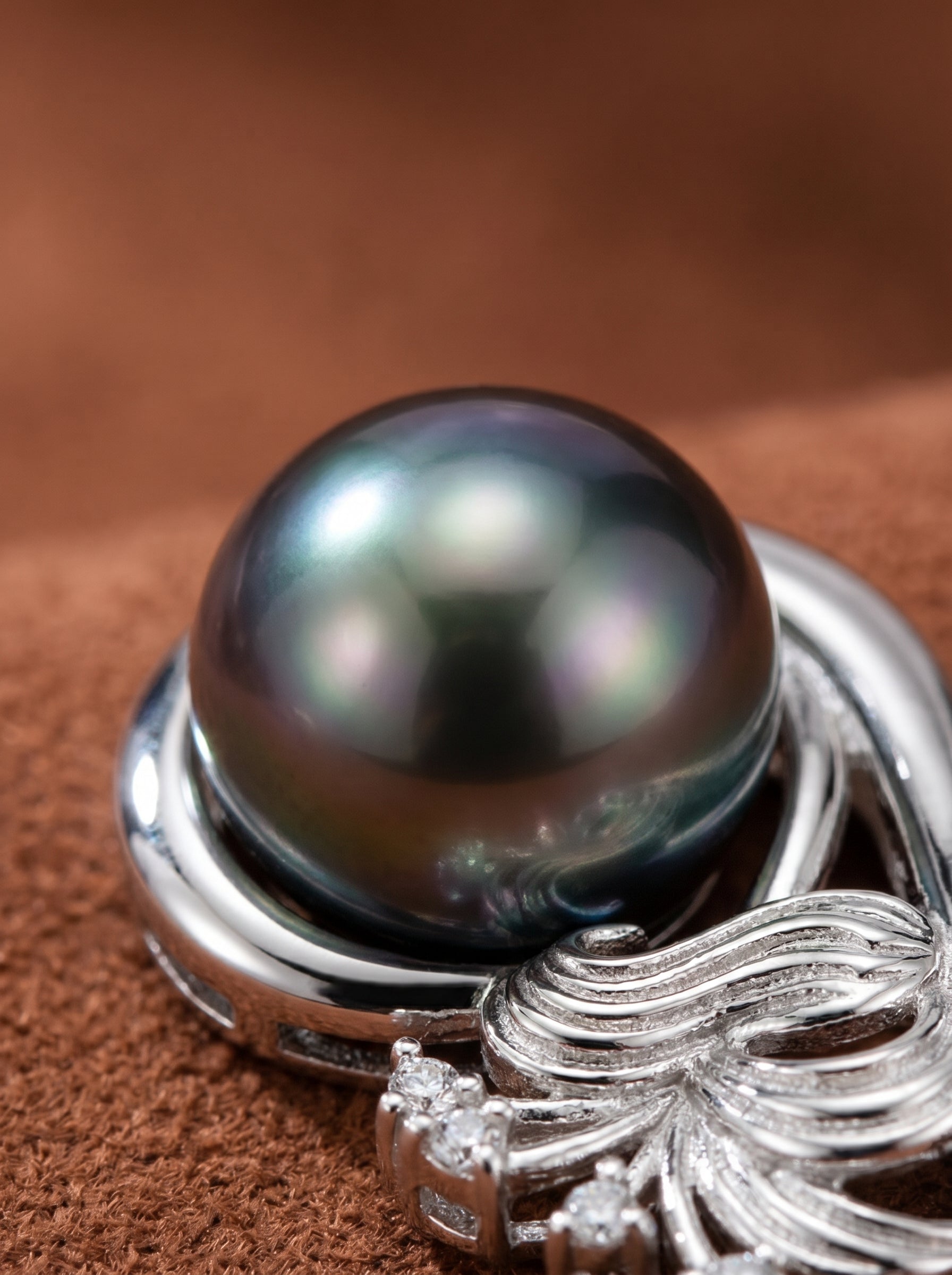 Close-up of the Enfold Swirl necklace featuring a lustrous 10mm round Tahitian pearl set in a polished silver-toned pendant with a flower motif and small accent stones. @pearl