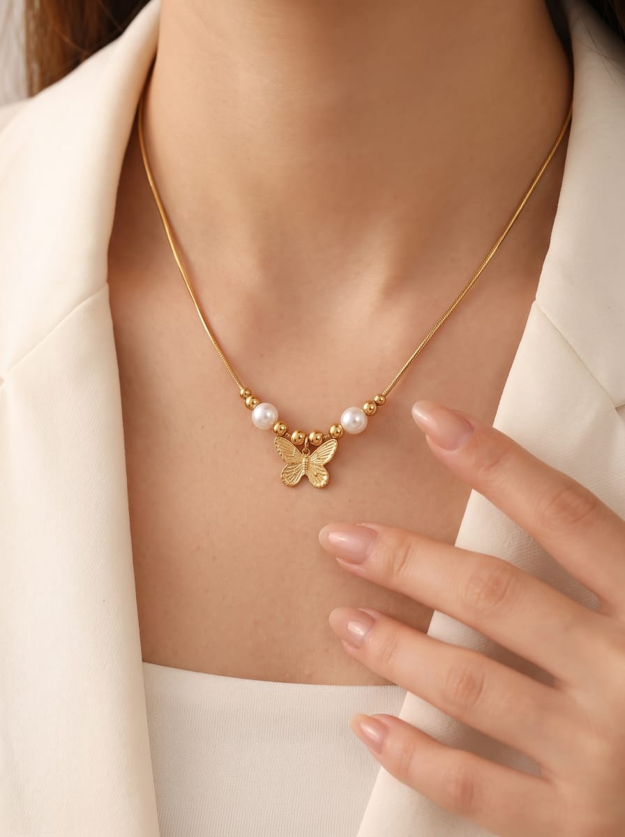 Collier pendentif papillon doré avec deux perles blanches d'eau douce et des perles dorées sur une chaîne serpent, montré sur une mannequin @model