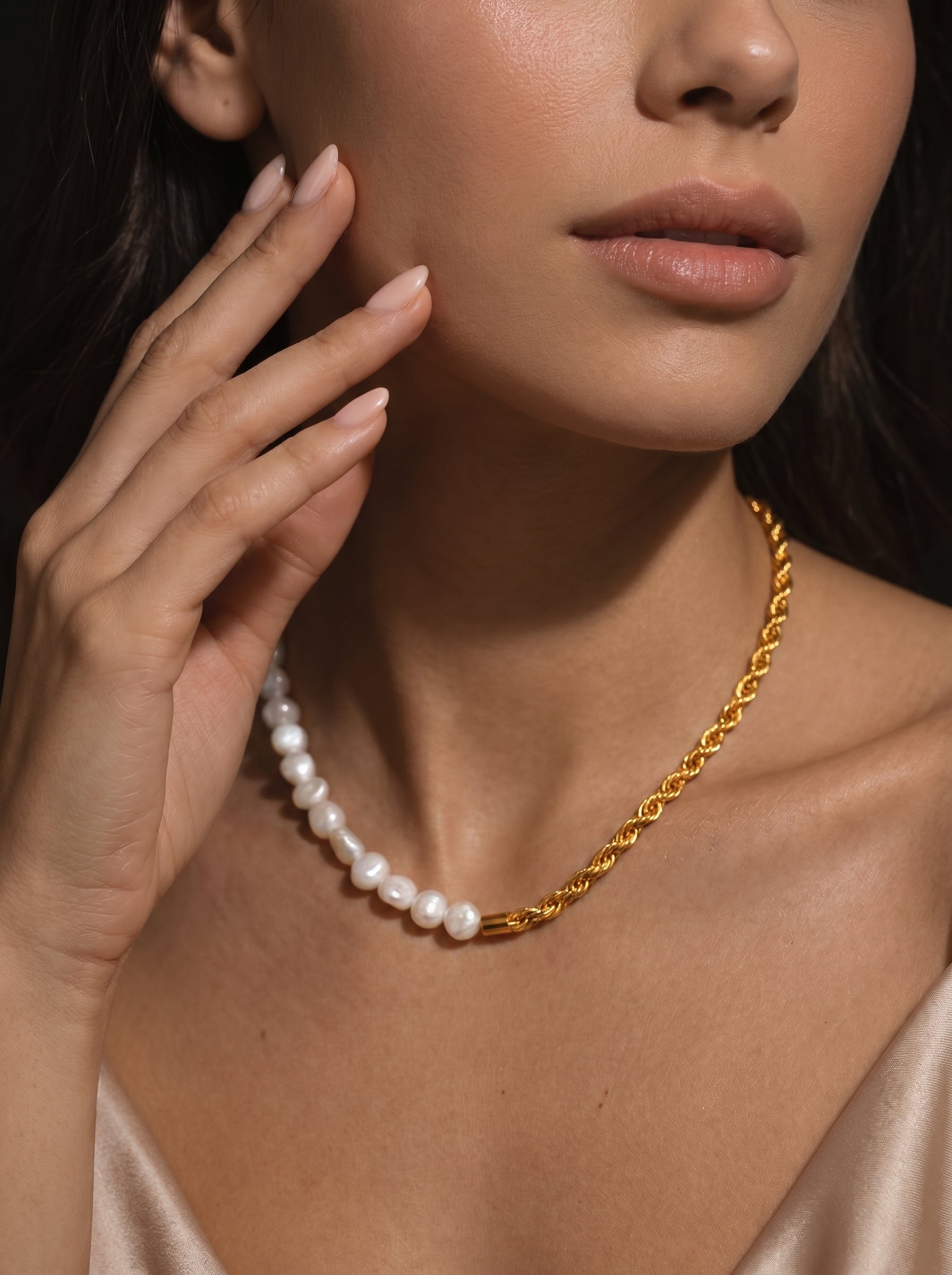 A gold rope chain necklace is combined with a strand of white freshwater pearls, worn by a model. @model