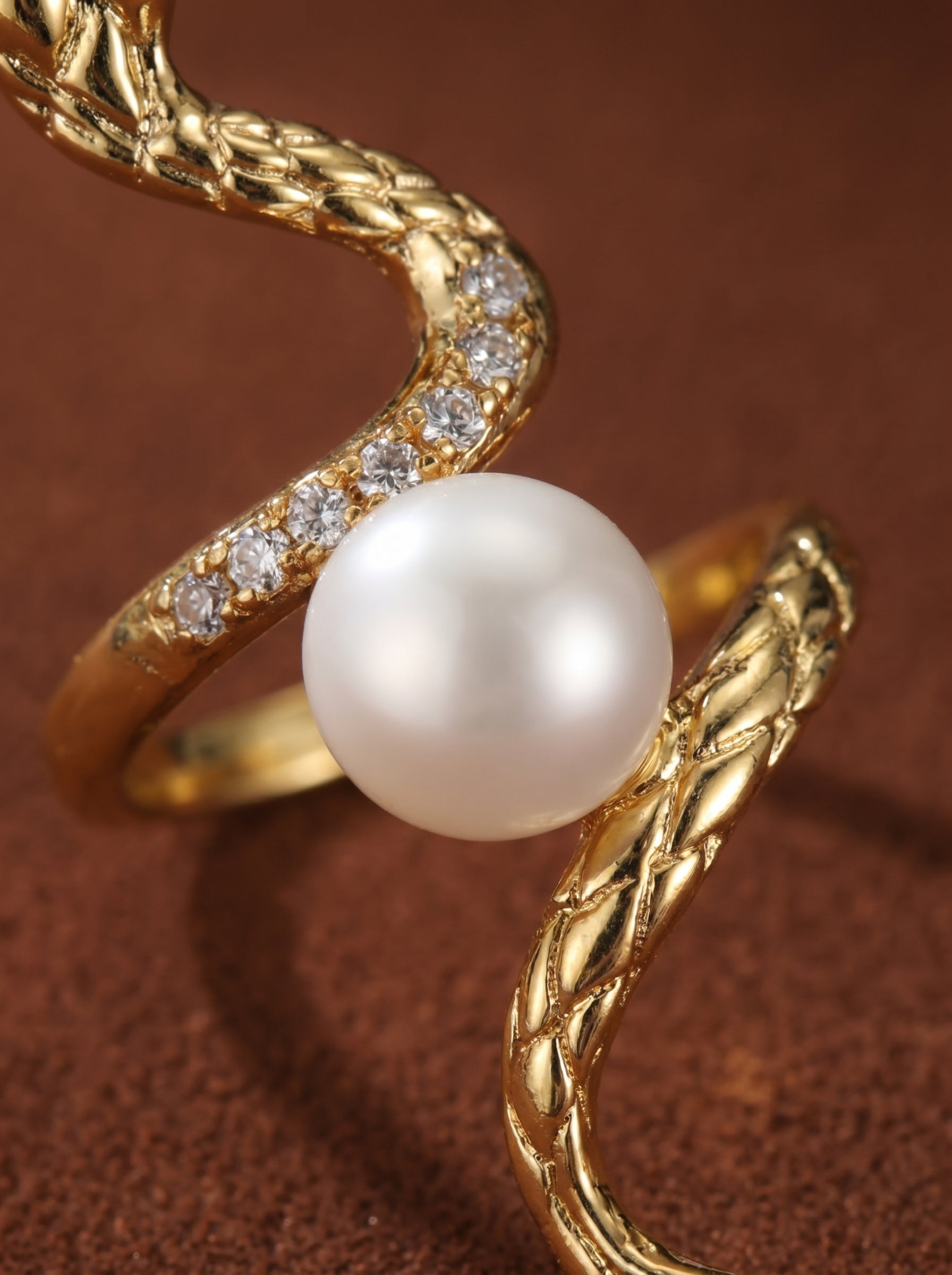Gold-tone snake cuff ring with textured scales and sparkling accent stones, embracing a luminous 8mm white button freshwater pearl. @pearl