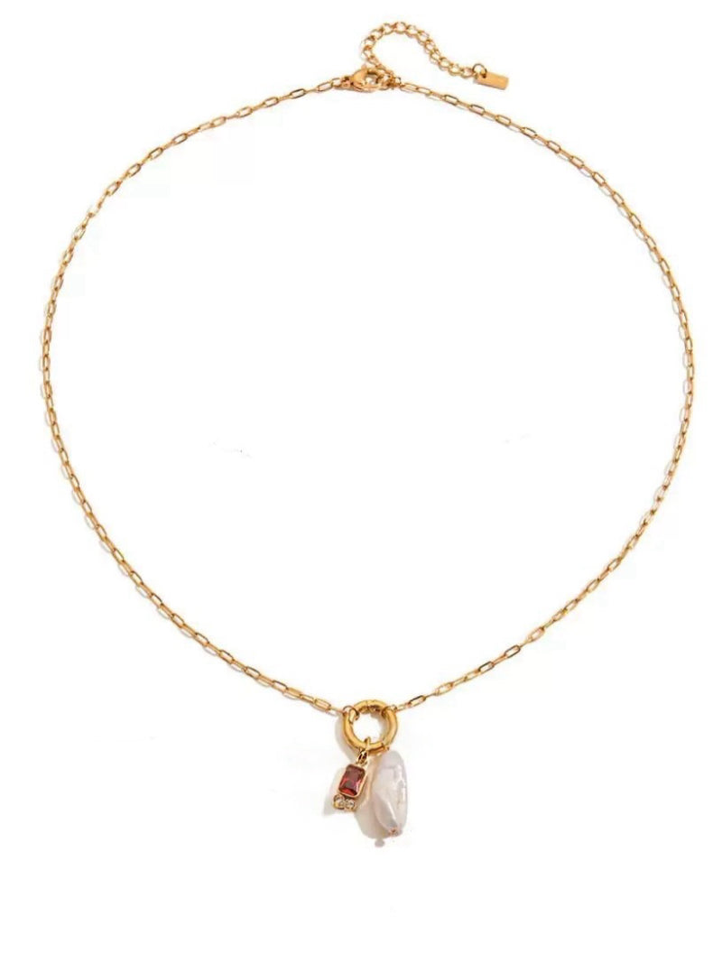 Gold-tone necklace featuring a single drop pendant with an irregular white freshwater pearl and a rectangular red gemstone set in a gold bezel.