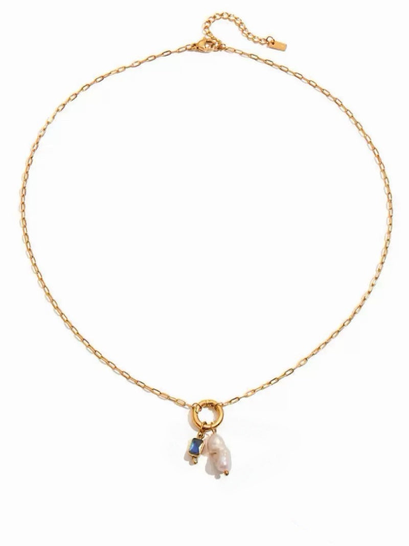 Gold-tone chain necklace featuring a circular pendant with a baroque freshwater pearl and a blue rectangular gemstone.