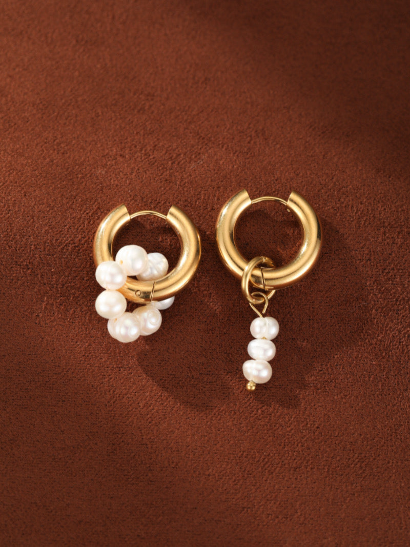 Créoles dorées asymétriques présentant des perles d'eau douce. Une boucle d'oreille a un groupe de perles sur la créole, et l'autre a une pendante de trois perles.