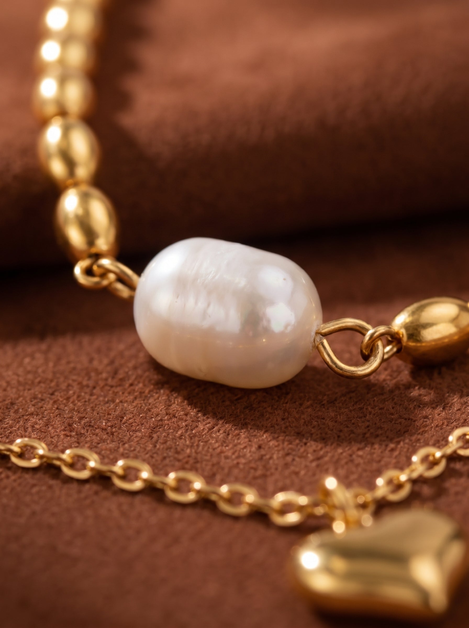Gilded Muse layered gold-tone chain necklace featuring a large, irregular white freshwater pearl and a polished gold heart pendant. @pearl