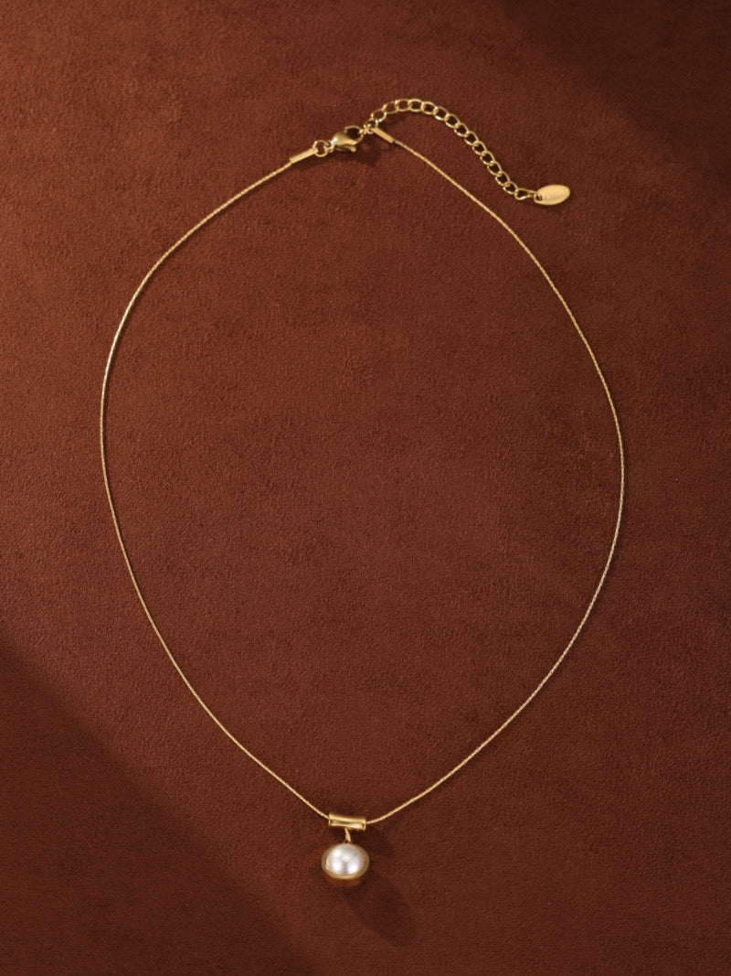 Glimpse - Gold-toned pendant necklace featuring a single, lustrous 10mm round white freshwater pearl suspended from a minimalist horizontal bar on a delicate chain.