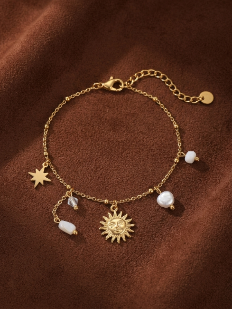 Gold-tone chain bracelet with a sun charm, a star charm, clear faceted beads, and irregular freshwater pearls.