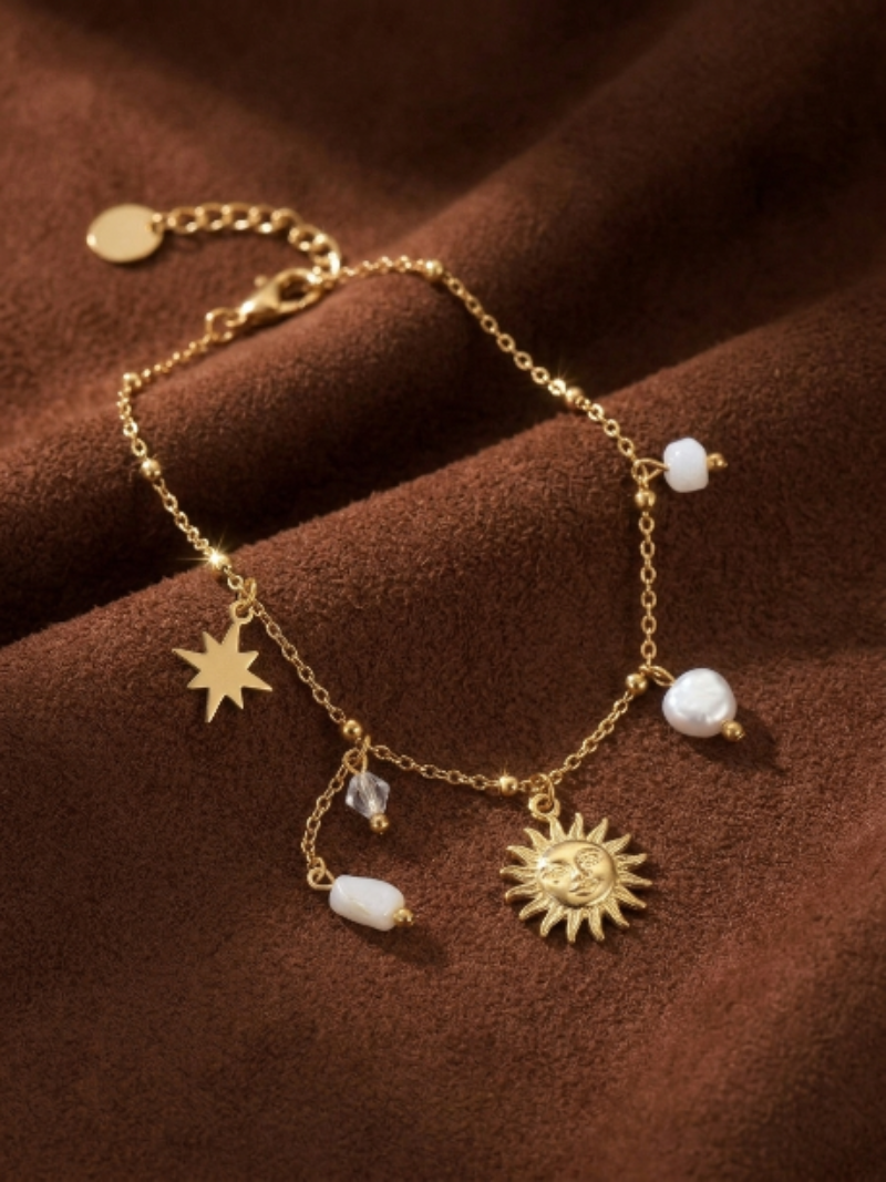 Gold-tone chain bracelet with a sun charm, star charm, Baroque freshwater pearls, and faceted beads.