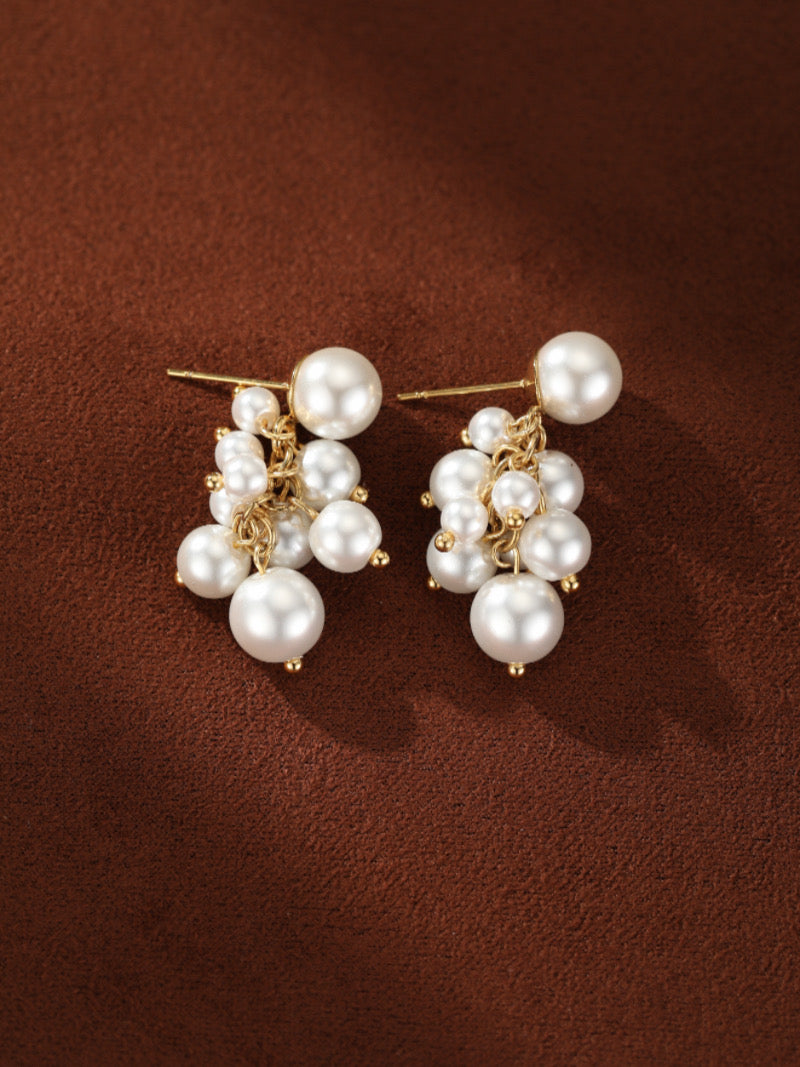 Boucles d'oreilles Glow Orb présentant une puce dorée avec une grande perle d'eau douce, d'où une chaîne dorée suspend un groupe dynamique de plus petites perles blanches d'eau douce en tailles 4 mm et 6 mm.