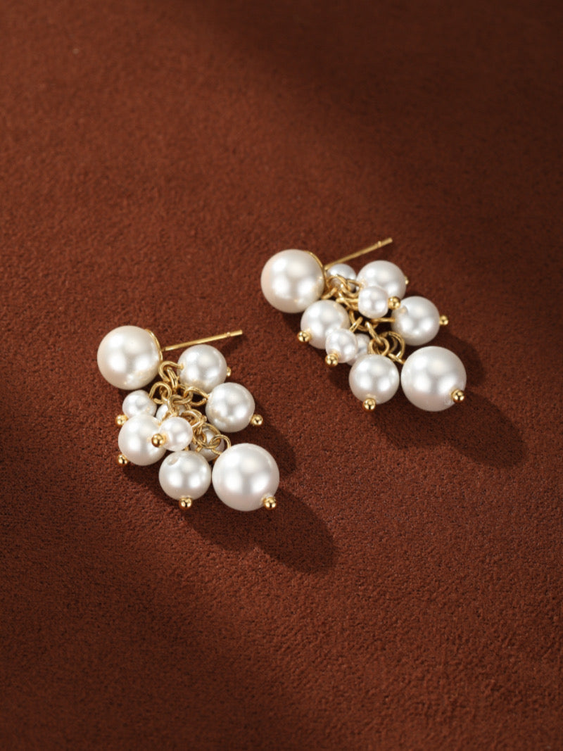 Boucles d'oreilles goutte en grappe Glow Orb en perle d'eau douce présentant une base puce avec une grande perle et une chaîne ton or suspendant un groupe de plus petites perles blanches.