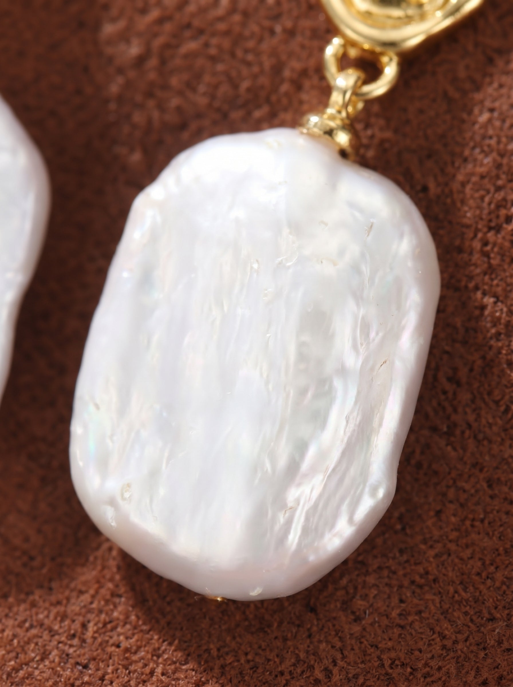 Close-up of a single Glyph Freshwater Pearl Visage Drop Stud Earring, showcasing the organically textured gold stud and the large, irregularly shaped white Baroque pearl pendant. @pearl