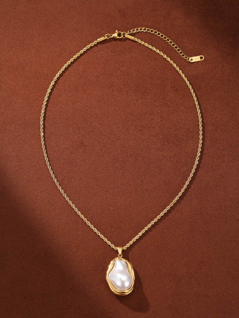A chunky gold-toned chain necklace with a unique, irregular white freshwater pearl pendant set in a fluid gold bezel. The pearl has a natural luster and baroque shape.