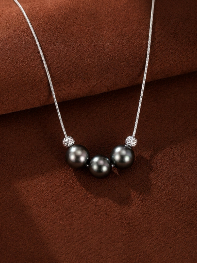 Three round Tahitian black pearls separated by textured silver beads on a delicate snake chain necklace.