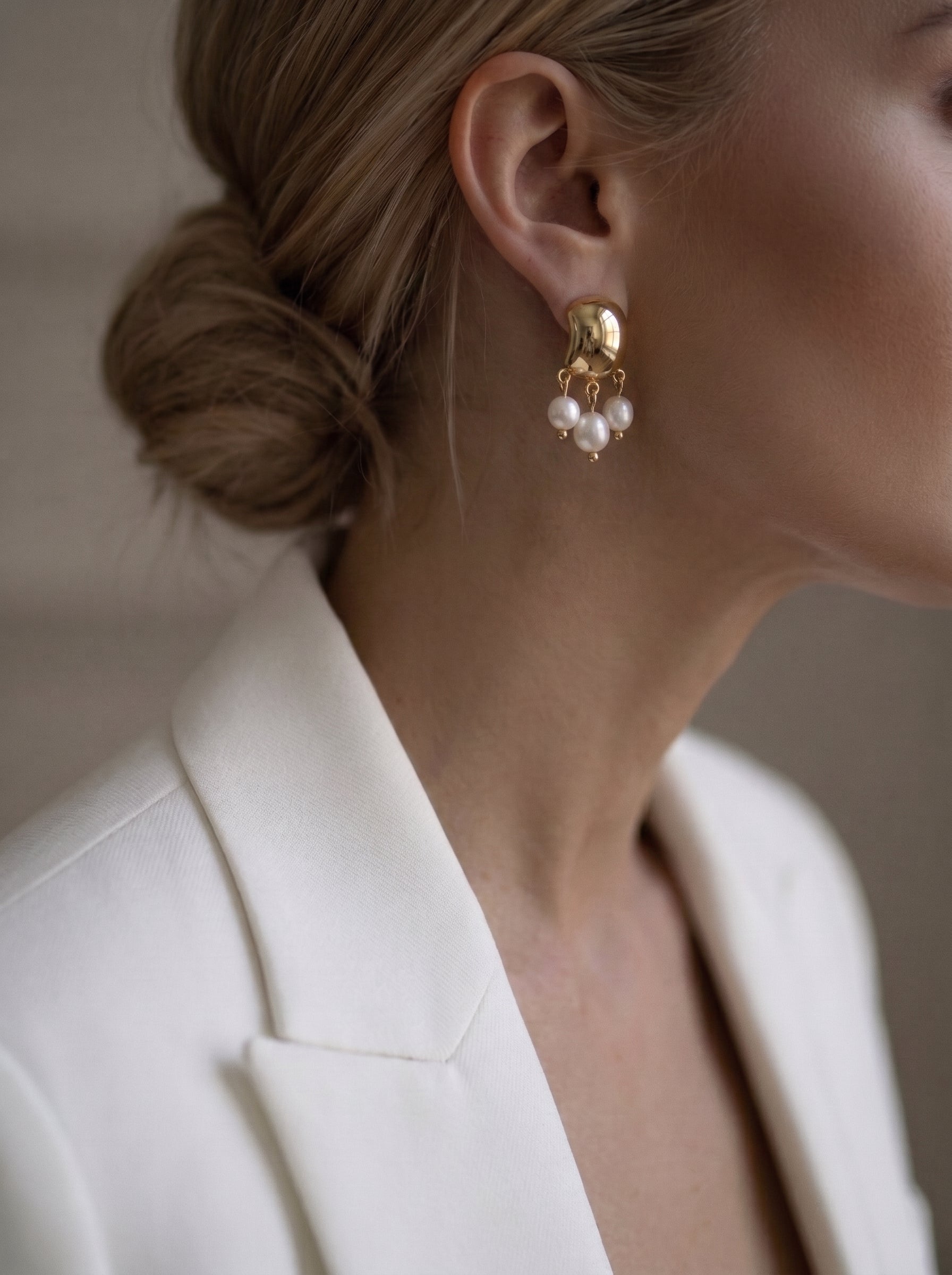 Harvest - Freshwater Pearl Drop Earrings with a hammered gold top and three dangling white seed pearls, worn by a woman in a white blazer. @lifestyle