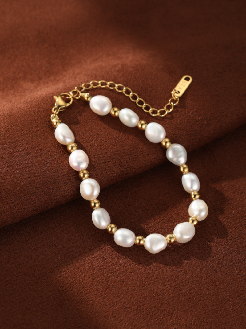 Inara - Freshwater Pearl Beaded Bracelet with gold-toned accents and adjustable clasp on a brown background.