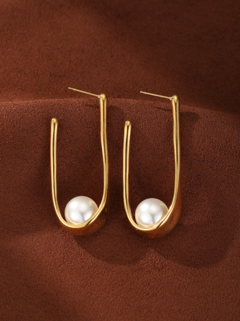 Boucles d'oreilles goutte sculptées en perle d'eau douce Incline présentant une lustrée perle blanche ronde d'eau douce de 5 mm bercée dans un cadre allongé en U ton or.