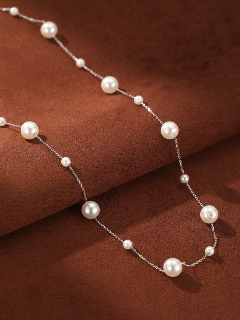 Journey - Imitation Pearl Long Chain Necklace with alternating 8mm and 4mm white imitation pearls on a delicate silver chain, displayed on a brown textured background. @pearl
