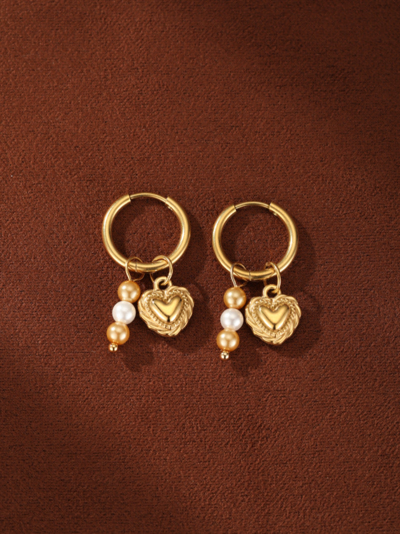 Gold-tone hoop earrings featuring a textured heart charm adorned with white and gold freshwater pearls.
