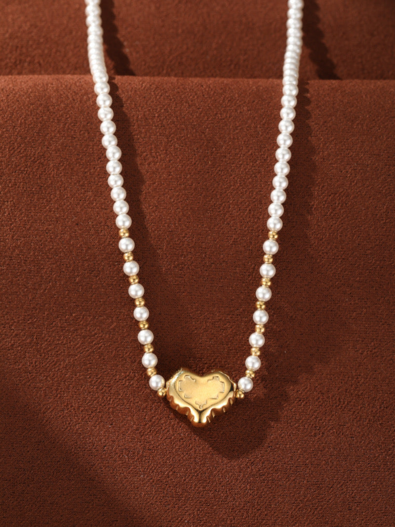 Vue en gros plan du collier pendentif cœur perlé Kindred en perle d'eau douce, révélant un délicat fil de perles blanches de 3 mm entrecoupées de petites perles accent dorées, centré par un pendentif cœur sculpté ton or.
