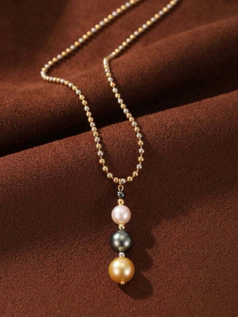 Luminance long pendant necklace featuring a vertical drop of three round pearls: white Akoya, black Tahitian, and golden South Sea, on a mixed-tone gold and silver ball chain.