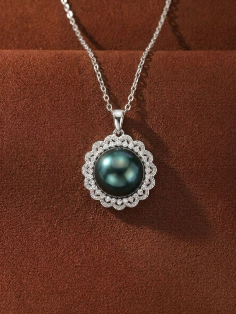 A black Tahitian Mabe pearl pendant necklace with a sunburst halo of white stones on a brown background.
