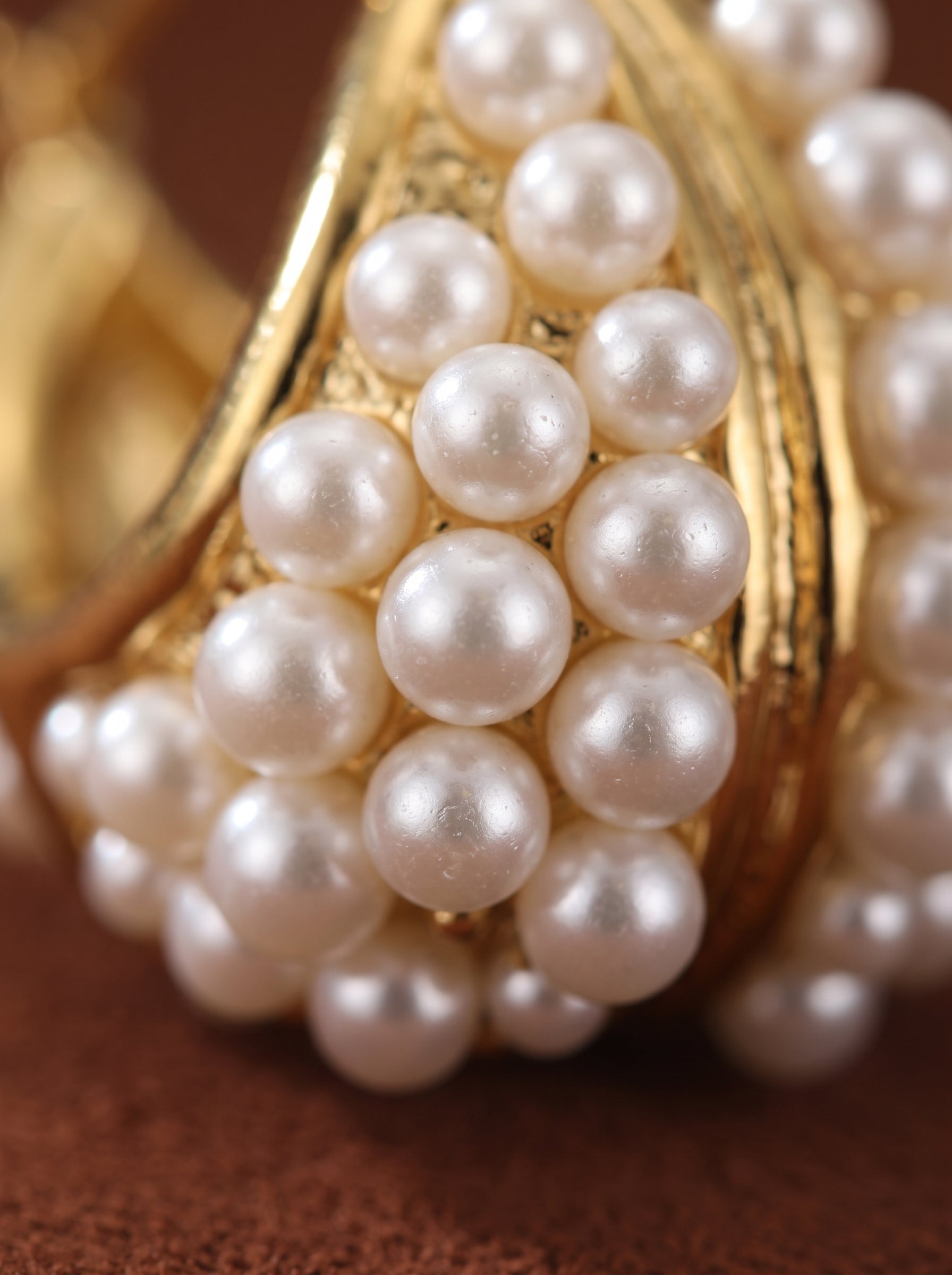 Close-up of Lush freshwater pearl hoop earrings, featuring a gold setting densely covered with lustrous 2mm white button freshwater pearls. @pearl