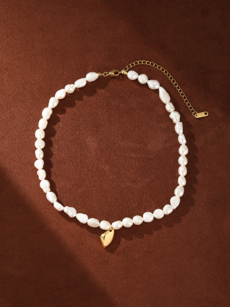 Collier ras-de-cou Lyrical présentant un fil de perles blanches irrégulières d'eau douce et un pendentif goutte abstrait moderne ton or, avec un fermoir mousqueton ton or et une chaîne d'extension.